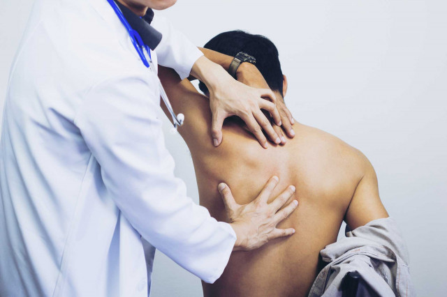 Therapie: Moderne Ansätze zur Behandlung - Ein Arzt untersucht den Rücken eines Mannes in einer medizinischen Umgebung.
